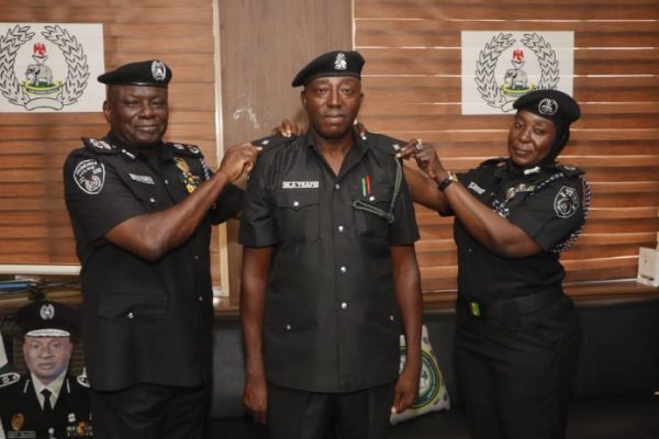 FCT police commissioner CP Benneth Igweh decorates one of the newly promoted officers at the command in Abuja on Wednesday.