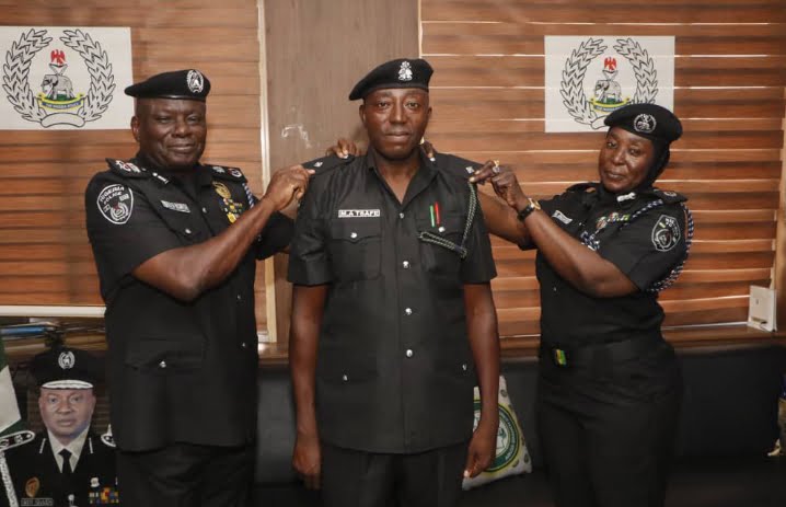 FCT police commissioner CP Benneth Igweh decorates one of the newly promoted officers at the command in Abuja on Wednesday.